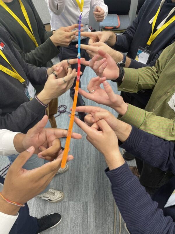 Students working together to lift a coloured stick